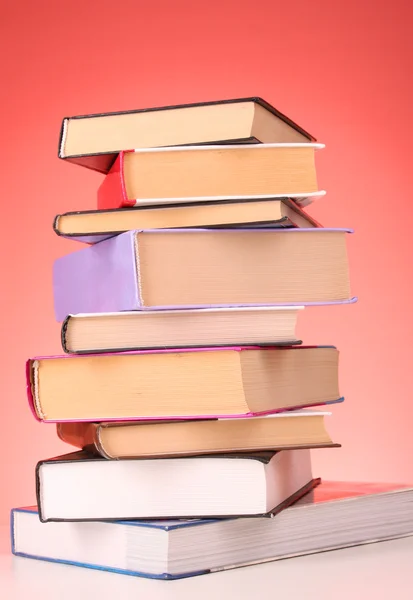 Böcker högen på bordet och röd bakgrund — Stockfoto