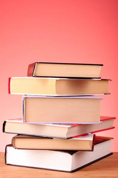Hromada knih na stole a červeném pozadí — Stock fotografie