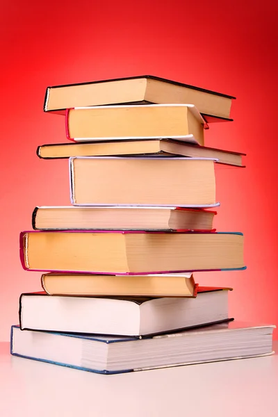 Hromada knih na stole a červeném pozadí — Stock fotografie