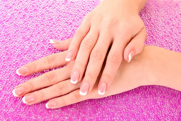 Belas mãos de mulher com manicure francês no fundo rosa — Fotografia de Stock