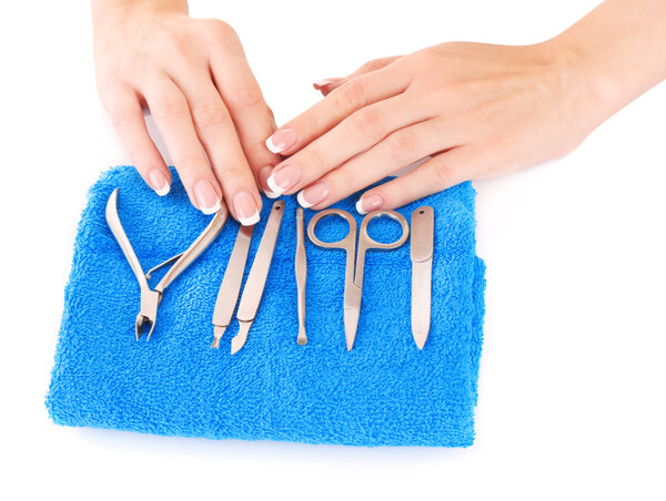 Woman's hands and manicure instruments on blue background