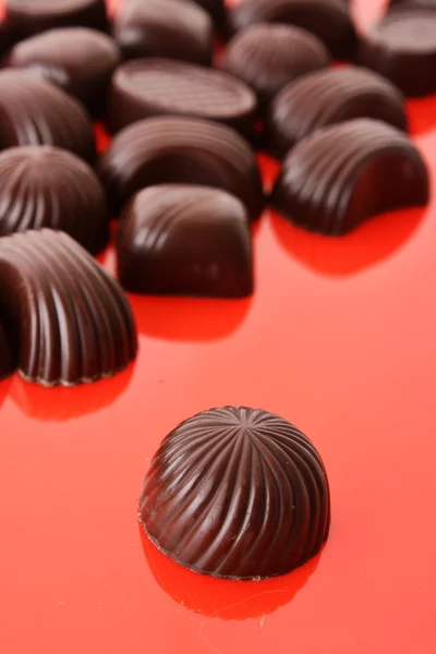 Různé čokoládové bonbony na červeném pozadí — Stock fotografie