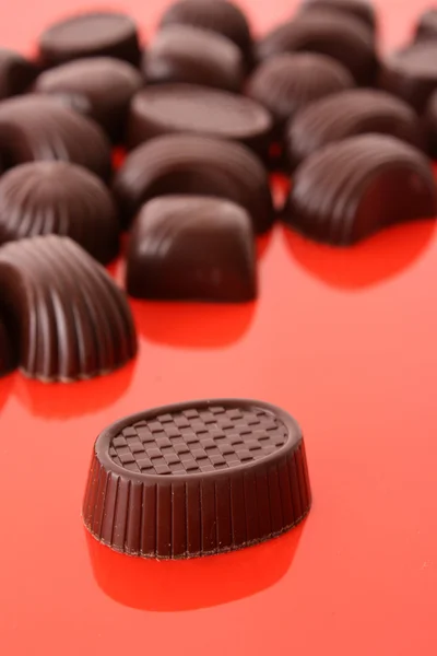 Doces de chocolate sortidas no fundo vermelho — Fotografia de Stock