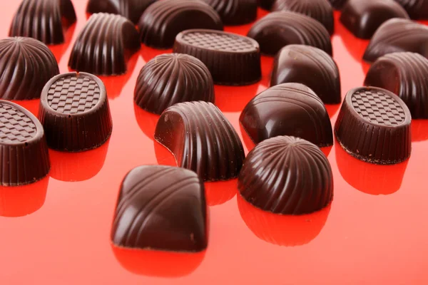 Válogatott csokoládé cukorka, piros háttér — Stock Fotó