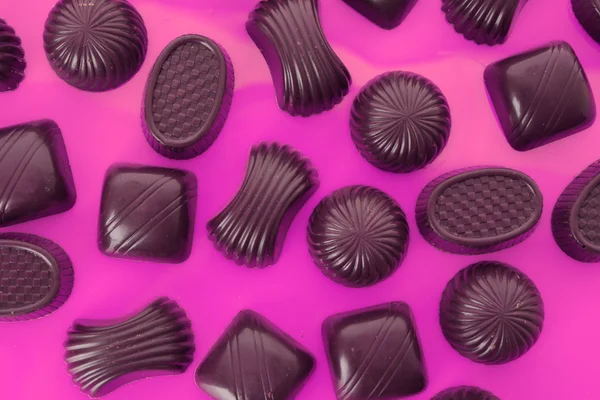 Assorted chocolate candies on pink background — Stock Photo, Image