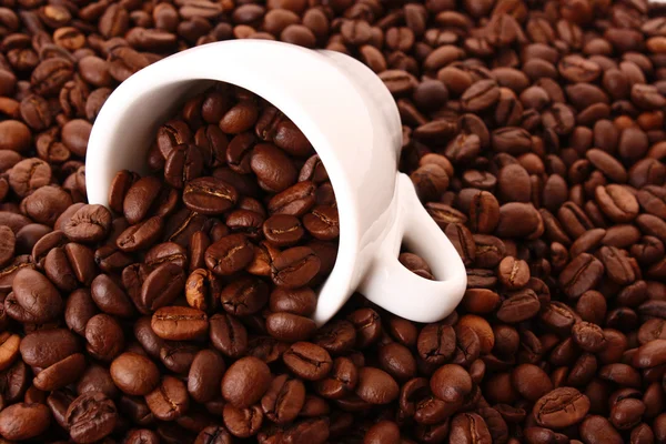 Małe białe filiżanka kawy z ziarna kawy na tle ziarna — Zdjęcie stockowe