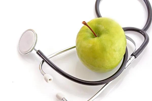 Stetoscopio e mela verde su sfondo bianco — Foto Stock