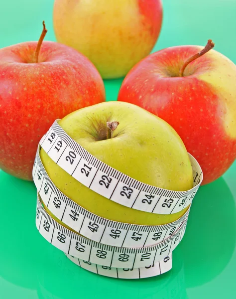 Vit måttband runt ett rött äpple som representerar bantning — Stockfoto