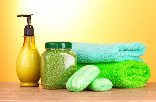 Соль для ванн, мыло и полотенце на желтом фоне — стоковое фото