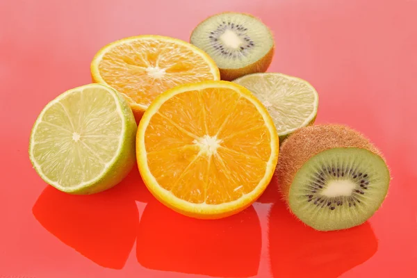 Orange and other fruits on red — Stock Photo, Image