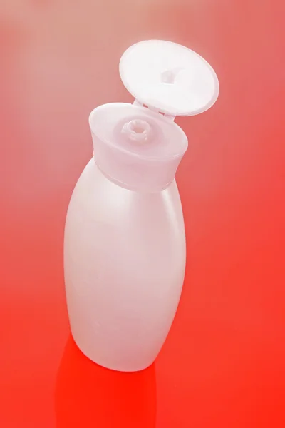 Розовая бутылка шампуня на красном фоне — стоковое фото