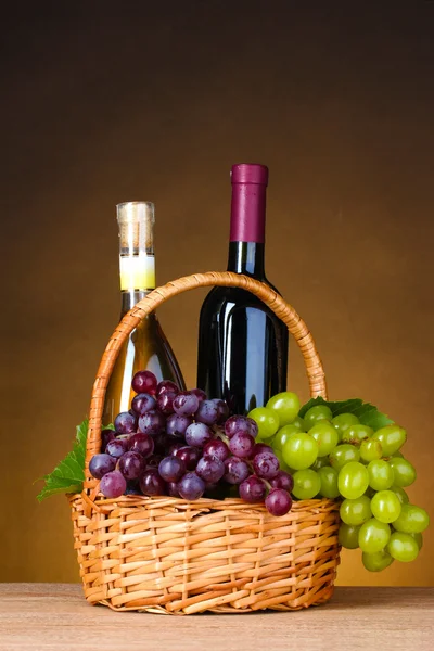 Бутылки вина и винограда в корзине — стоковое фото