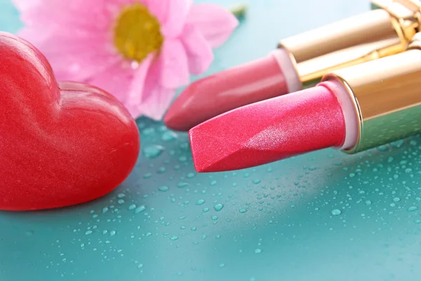 Two new lipsticks and pink flower on blue background — Stock Photo, Image