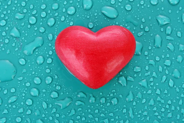 Мыло в форме сердца на фоне синих капель воды — стоковое фото