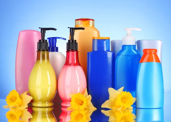 Bottles of health and beauty products on blue background with re — Stock Photo, Image