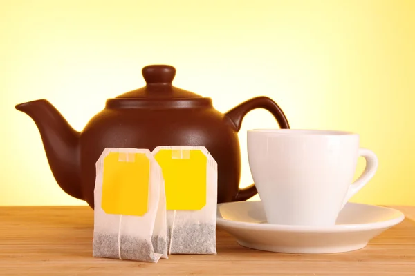 茶袋，茶壶在黄色背景上的特写 — 图库照片