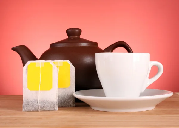 Close-up of tea bag and teapot on yellow background — Stock Photo, Image