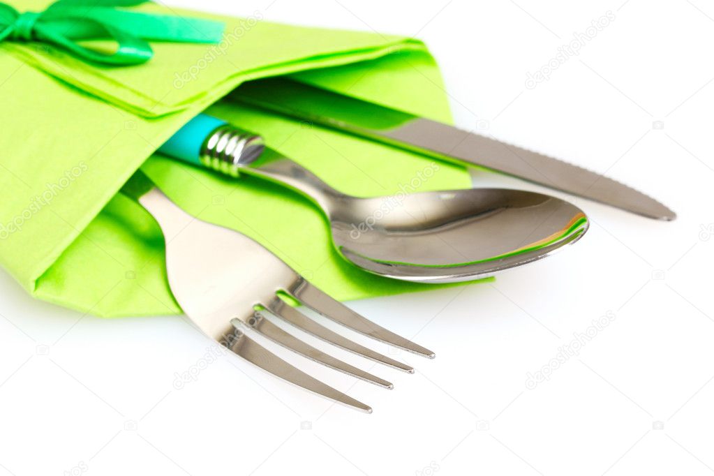 Knife, fork and spoon in green cloth, isolated on white