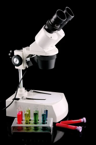 Laboratory metal microscope and test tubes with liquid on the b — Stock Photo, Image