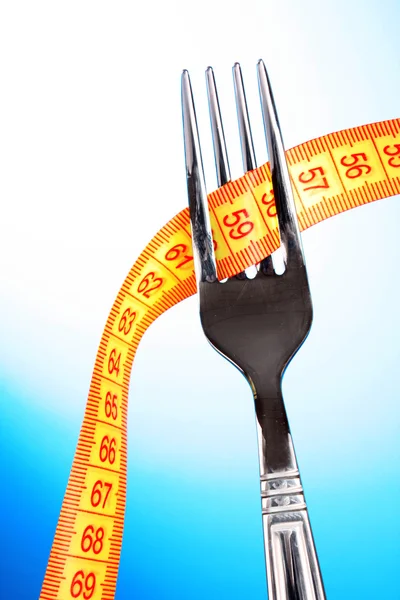 Fork and measuring tape on blue background — Stock Photo, Image