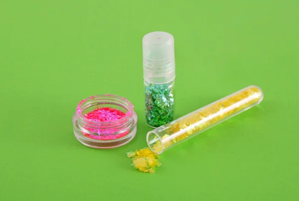Lantejoulas de cor para manicure no fundo verde — Fotografia de Stock