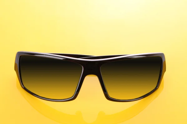 Sarı arkaplanda siyah güneş gözlüğü — Stok fotoğraf