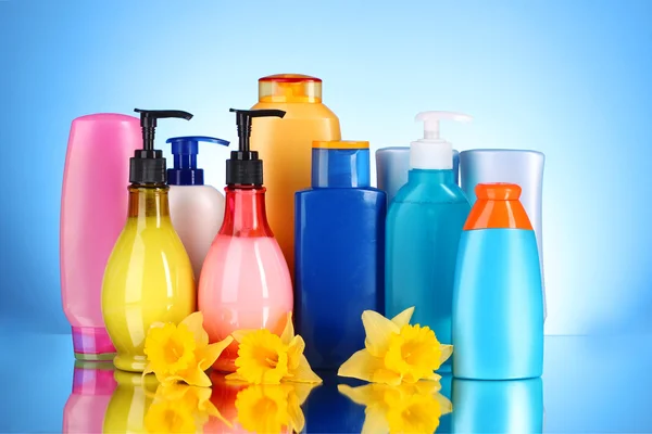 Bottles of health and beauty products on blue background with re — Stock Photo, Image