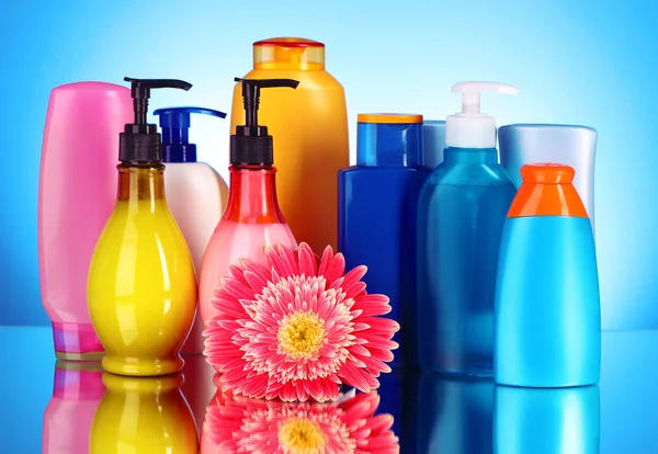 Botellas de productos de salud y belleza sobre fondo azul con re — Foto de Stock