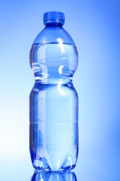 Пляшка води на синьому фоні — стокове фото