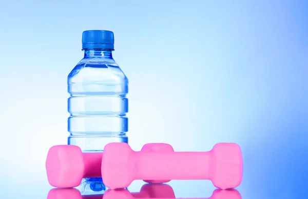 Manubri e bottiglia di acqua dolce su blu — Foto Stock