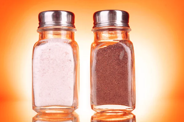 Glas zout en peper shakers op gele achtergrond — Stockfoto