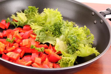 Frying pan with vegetables on the table clipart