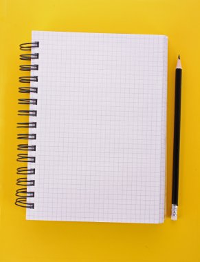 Sarı arkaplanda kurşun kalem olan defter