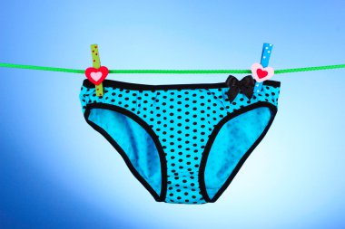 Woman's panties hanging on blue background clipart