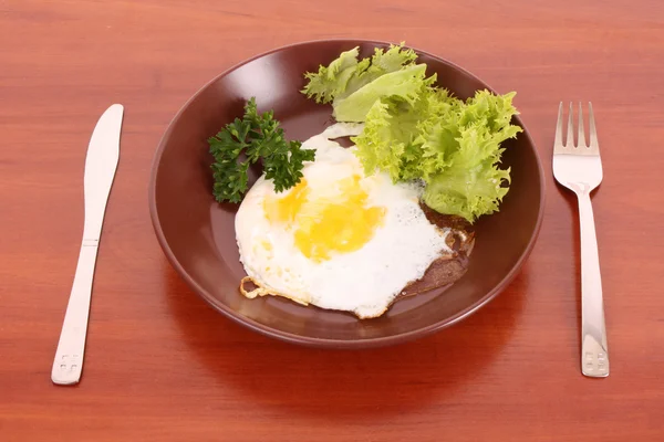 stock image Frying egg with fork and knife on the table