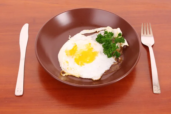 Τηγάνισμα το αυγό με το πηρούνι και μαχαίρι στο τραπέζι — Φωτογραφία Αρχείου