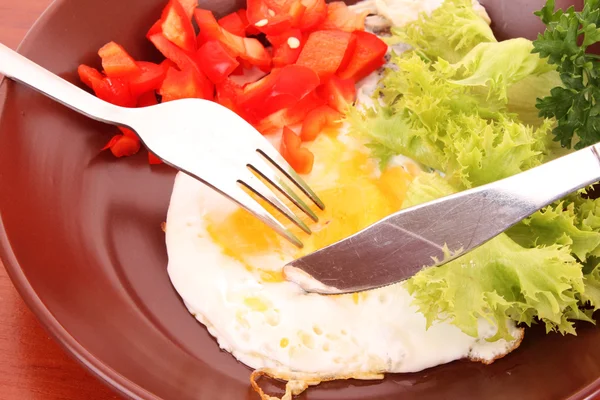 Steka ägg med gaffel och kniv i tabellen — Stockfoto