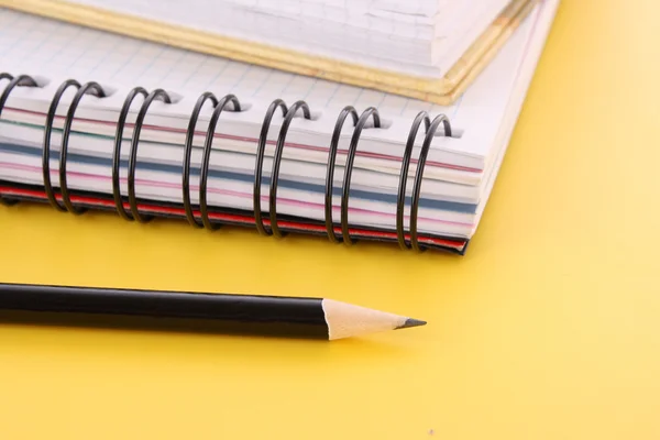 Ноутбук с карандашом на желтом фоне — стоковое фото