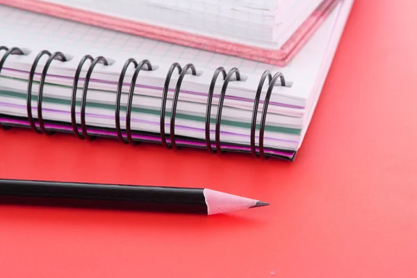Jegyzetfüzet ceruzával a piros háttér — Stock Fotó