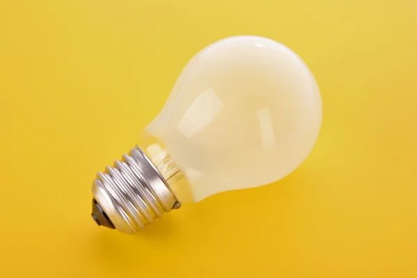 Лампочка на желтом фоне — стоковое фото