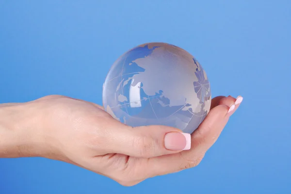 Niebieski Kryształowy Globus w ręku na niebiesko — Zdjęcie stockowe