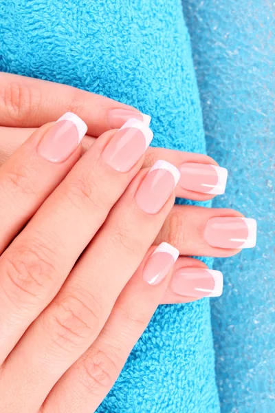 Beautiful woman hands with french manicure on blue background — Stock Photo, Image