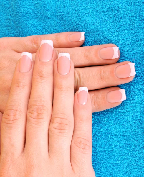 Mooie vrouw handen met Frans manicure op blauwe achtergrond — Stockfoto