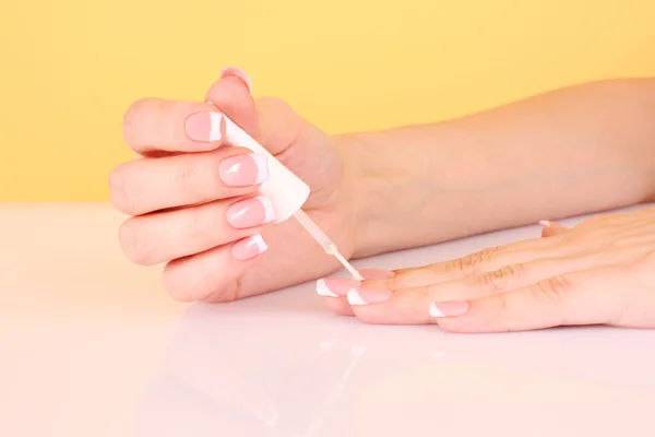 Beautiful woman hands with french manicure on yellow background — Stock Photo, Image