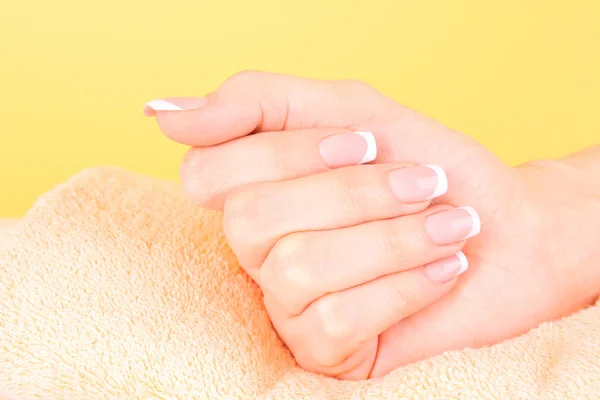 Beautiful woman hands with french manicure on yellow background — Stock Photo, Image