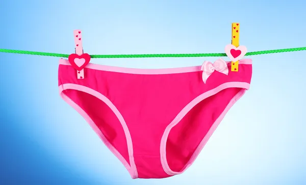 Woman's panties hanging on blue background — Stock Photo, Image