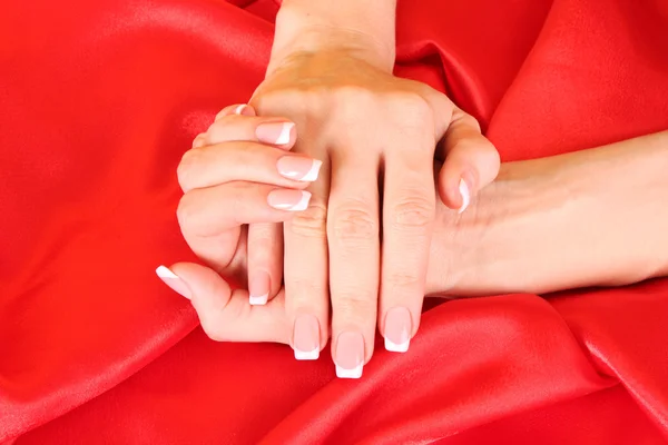 Beautiful woman hands with french manicure on red background — Stock Photo, Image