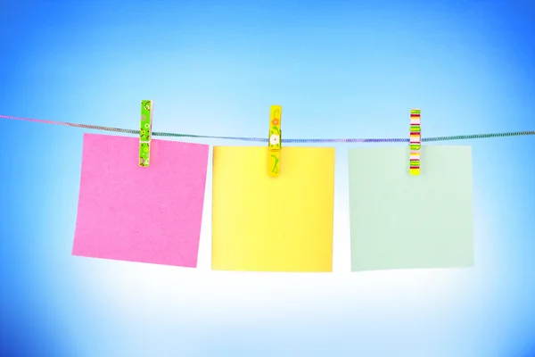 Blank paper sheets on a clothes line on a blue background — Stock Photo, Image