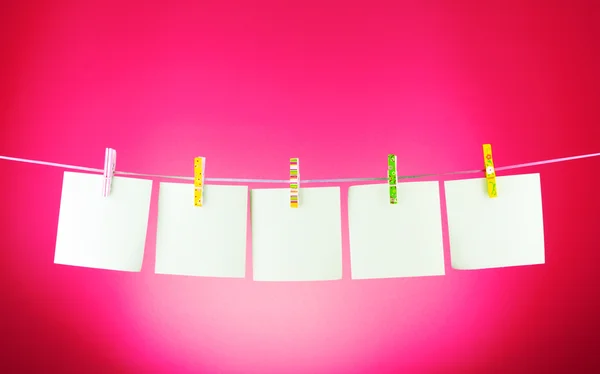 Fogli di carta bianchi su una linea di vestiti sullo sfondo rosa — Foto Stock