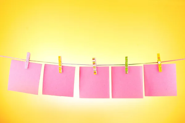 Leere Papierblätter auf einer Wäscheleine vor dem gelben Hintergrund — Stockfoto